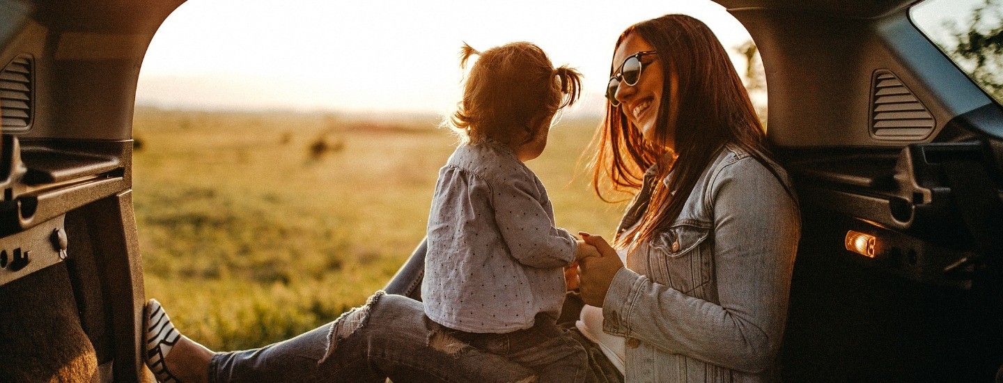 Woman playing with her daughter in the back of a car